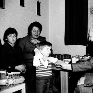 Family gathering around a birthday cake.