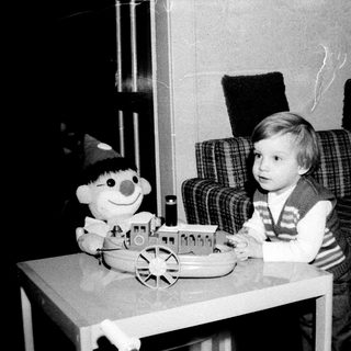 Young child playing with toy train and doll.