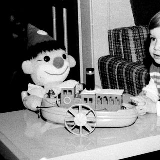 Young child playing with toy train and doll.