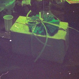 Dark room with illuminated green plants, scattered items, and a laser pointer.