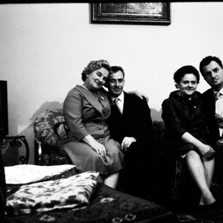Four people posing together indoors, mid-20th century.