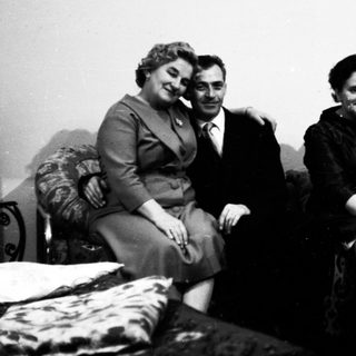 Four people posing together indoors, mid-20th century.