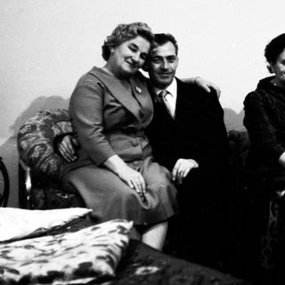 Four people posing together indoors, mid-20th century.