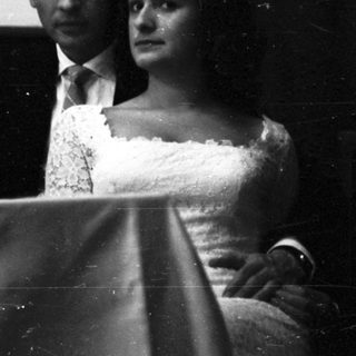 Couple seated at a piano, formal attire.