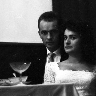 Couple seated at a piano, formal attire.