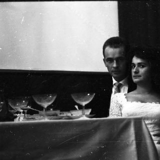Couple seated at a piano, formal attire.
