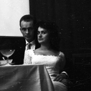 Couple seated at a piano, formal attire.