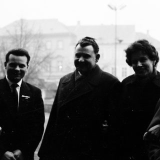Four individuals posing together outdoors in mid-20th-century attire.