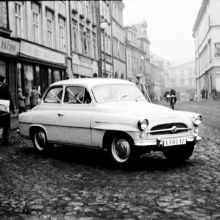 Classic car parked on cobblestone street in European town.