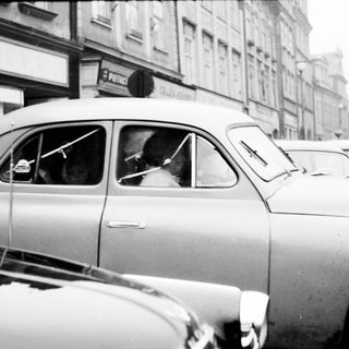 Taxi driver in vintage car on city street.