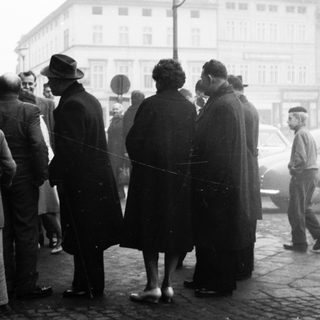 People queuing outside in a city street.