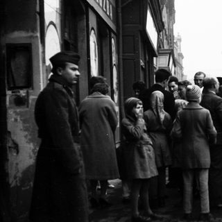 People queuing outside a building during post-war period.