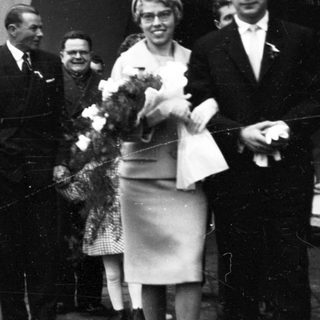 Funeral procession with mourners carrying floral wreaths.