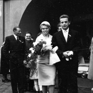 Funeral procession with mourners carrying floral wreaths.