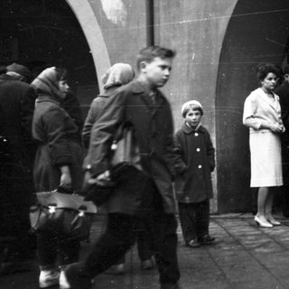 People gathered outdoors near arched entranceway.