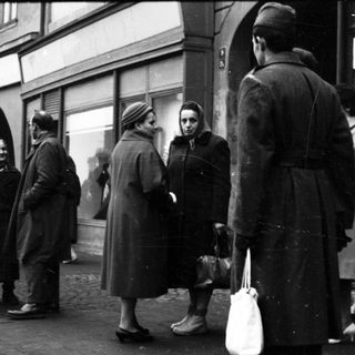 People queuing outside a store during mid-20th century.