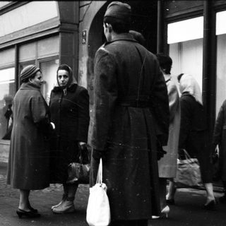 People queuing outside a store during mid-20th century.