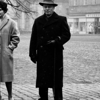 Three people posing outdoors in winter clothing, 1950s-era city square.