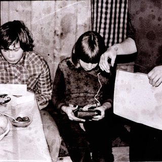 Two children playing with electronic devices at a table with food.