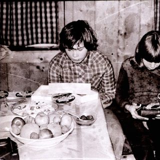Two children playing with electronic devices at a table with food.