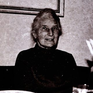 Elderly woman smiling indoors, mid-20th century.