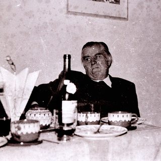 Old man toasting at a formal dinner table.