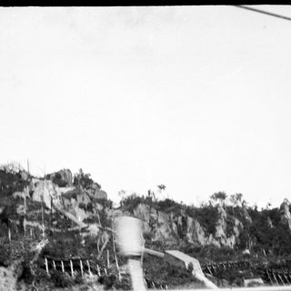 Rural road with rocky terrain and water tank.