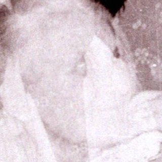 A woman in vintage nightwear holding a sleeping child.