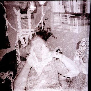 A woman in vintage nightwear holding a sleeping child.