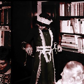 Magician performing trick with handkerchief in library setting.