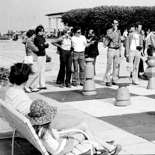 People playing giant outdoor chess on a large board.