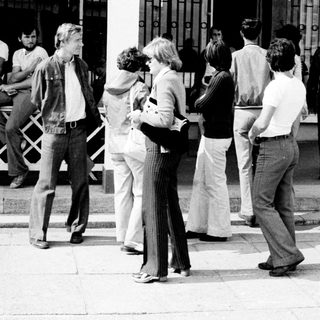 Group of people waiting outside a building entrance.