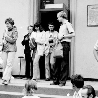 People gathered outside a building entrance in the 1970s-80s.