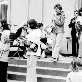 People gathered outside a building entrance in the 1970s-80s.
