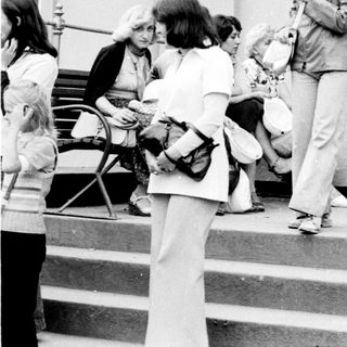 People gathered outside a building entrance in the 1970s-80s.