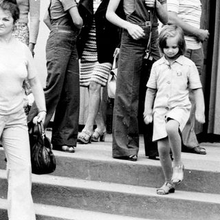 People exiting building during 1970s era.