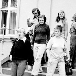 People exiting building during 1970s era.