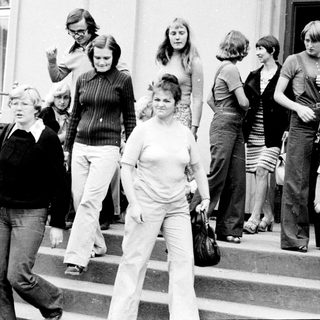 People exiting building during 1970s era.