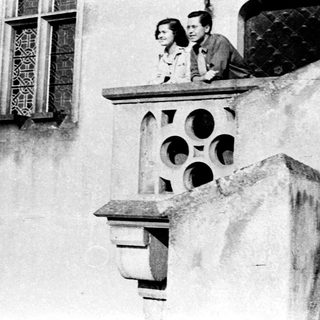 Two people leaning on a balcony railing.