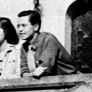 Two people leaning on a balcony railing.