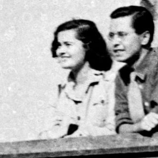 Two people leaning on a balcony railing.