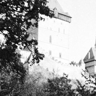 Medieval castle tower with person walking on overgrown path.