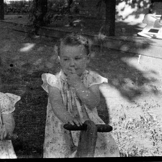 Two young children posing outdoors with toy wagons.