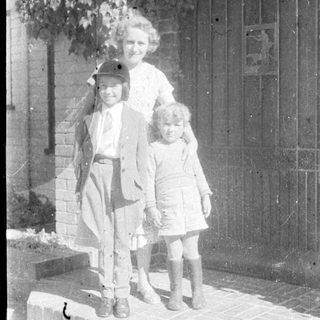 Family portrait with three children and adult outdoors.