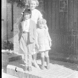 Family portrait with three children and adult outdoors.