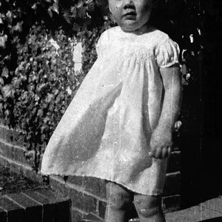 Young girl in vintage dress standing outdoors.