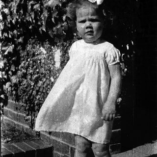 Young girl in vintage dress standing outdoors.