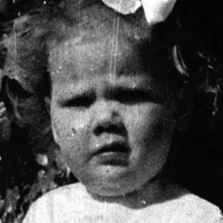 Young girl in vintage dress standing outdoors.