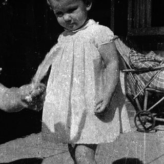 Young child holding adult's hand outdoors.