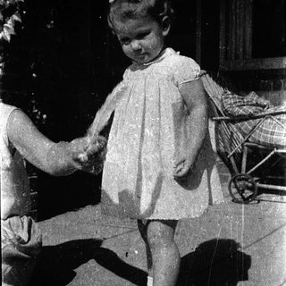 Young child holding adult's hand outdoors.